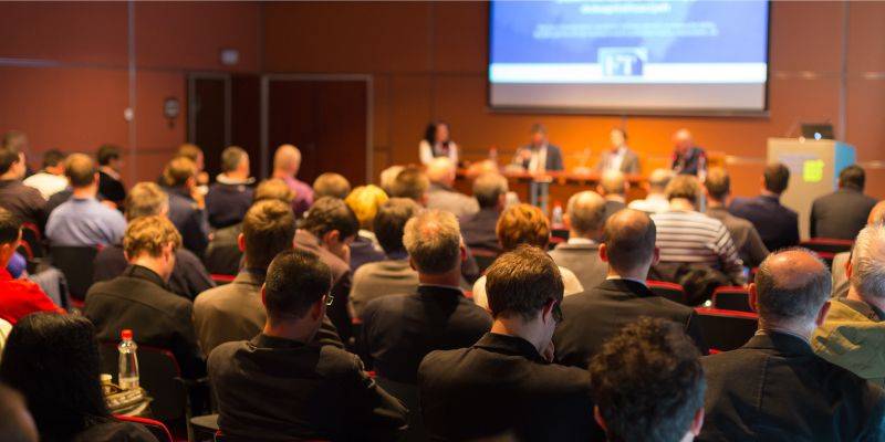 Black and white image of audience with hands raised, capturing concert energy.